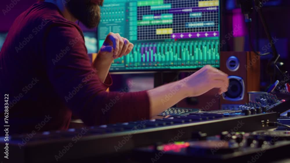 Music composer producing soundtracks using stereo panel controls and soundboard, twisting pre amp knobs for mixing and mastering tunes. Sound engineer adjusting volume in home studio. Camera A.
