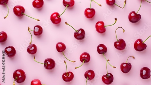 Fresh ripe cherries scattered on a pink background. Flat lay composition with a summer and healthy eating theme.