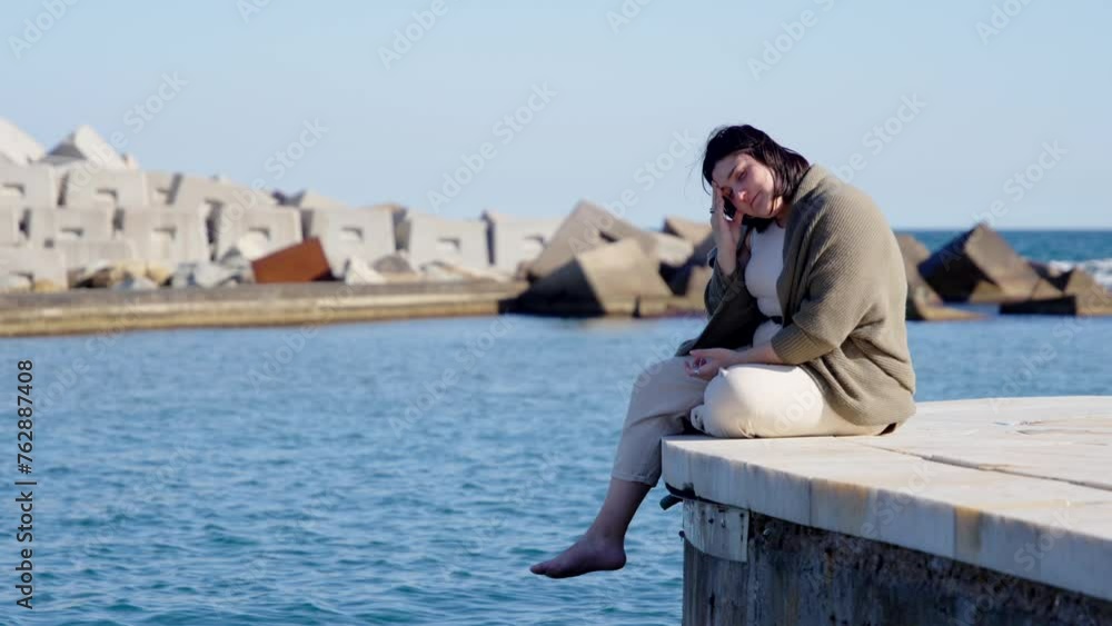 Sad curvy woman thinking at seaside. Loneliness and depression concept.