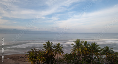 panoramic view of the beach at sunrise with palm trees and waves for surfing in Palabuhanratu, Sukabumi, west Java, Indonesia photo