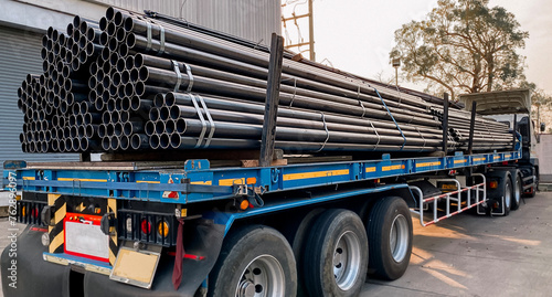 Trucks with long trailers carry rebar for building construction. Construction steel ready to be delivered to customers, steel transport vehicles, black steel pipes, structural steel.