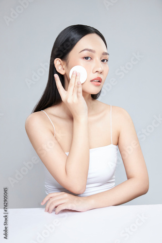 Attractive young Asian woman smile and uses cotton pad with toner for cleaning make up feeling so fresh and clean with healthy skin, isolated on white background.