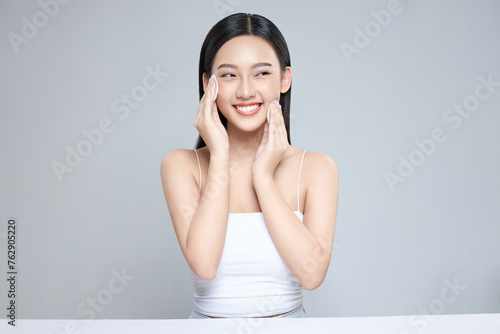 Attractive young Asian woman smile and uses cotton pad with toner for cleaning make up feeling so fresh and clean with healthy skin, isolated on white background. photo