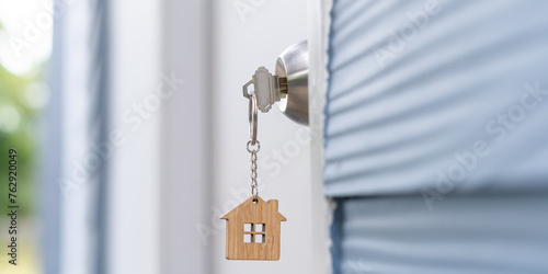 Landlord key for unlocking house is plugged into the door. Second hand house for rent and sale. keychain is blowing in the wind. mortgage for new home, buy, sell, renovate, investment, owner, estate © Shisu_ka