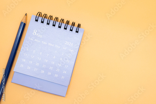 2024 August Calendar and pencil isolated on orange background. planning for business or travel concept. Copy space for text.