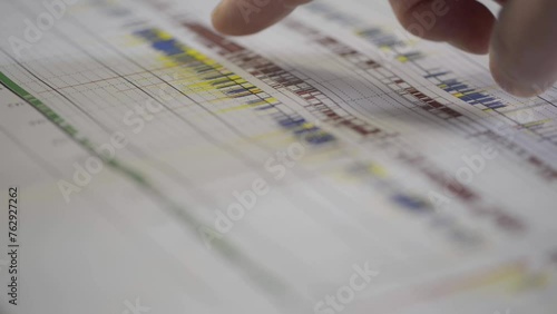 Close-up of a finger pointing at a detailed schedule or timeline chart photo