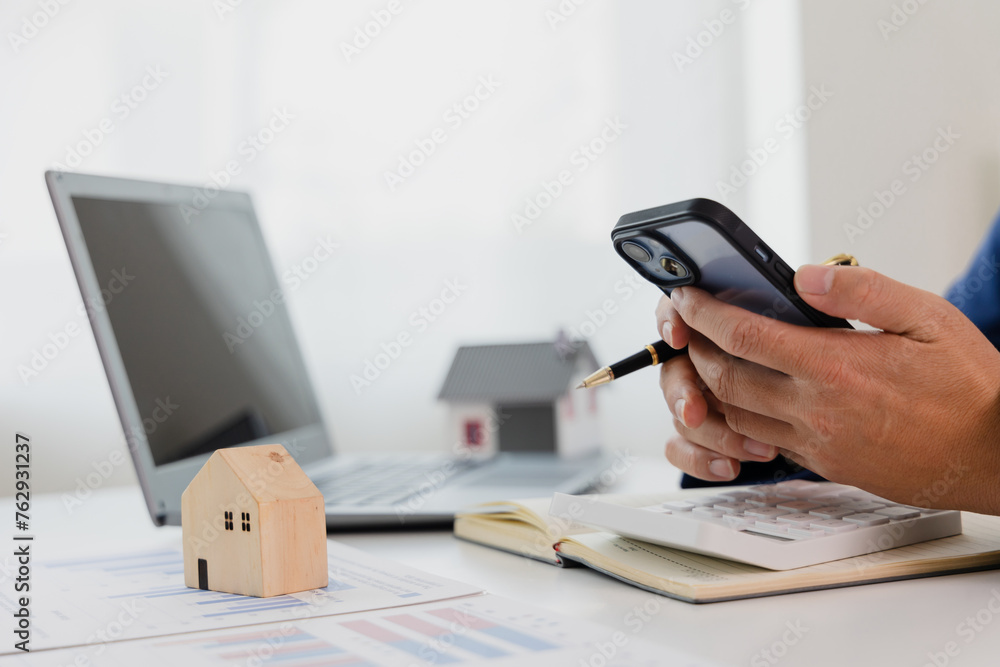 Fototapeta premium Man in a suit doing property tax calculations using a calculator of a house model