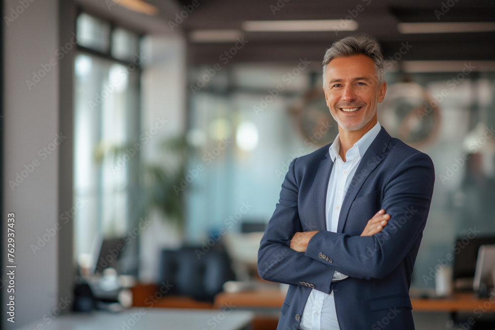 Fototapeta premium Caucasian business man portrait. Handsome, happy man wearing suit standing in modern office. Smiling white male manager looking at camera in workplace area.