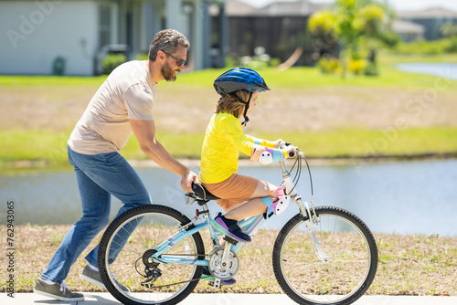 Happy Fathers day. Father and son in a helmet riding bike. Little cute adorable caucasian boy in safety helmet riding bike with father. Family outdoors summer activities. Childhood and fatherhood. © Volodymyr