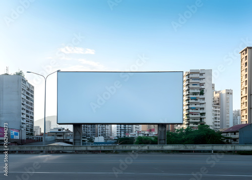 Illuminated Billboard Mockup, in the Background Towers Over Bustling Streets © MAJGraphics