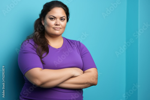 A woman in a purple shirt is standing in front of a blue wall