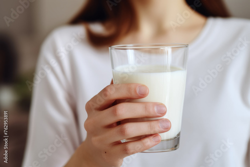 A woman is holding a glass of milk
