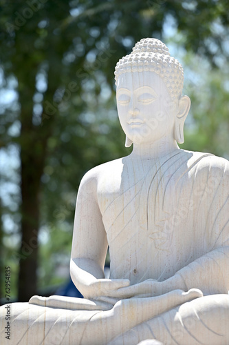 White stone Buddha statue in meditation position Located amidst nature