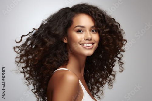 A woman with curly hair is smiling and looking at the camera