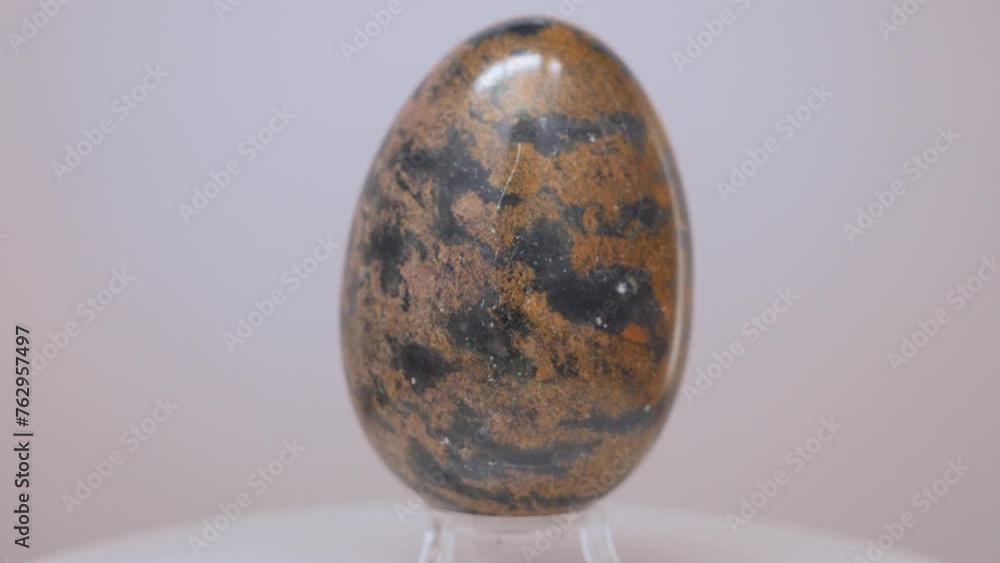 Large Granite egg rotating slowly on a turntable in front of a white background. Large Granite egg rotating slowly on a turntable in front of a white background.