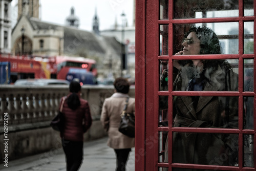 A woman stands within the quintessential red telephone box on London's streets.