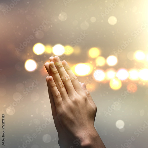 Close up man hand pray with defocused light background.