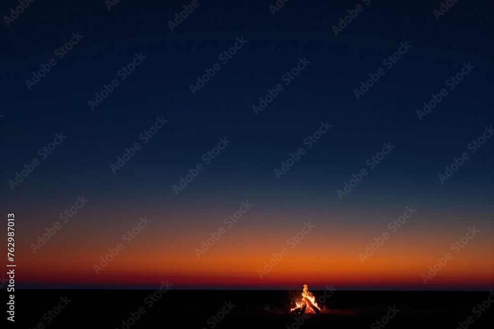 Evening campfire on the vast, open plains. Dusk. Gradient sky. Solitude. A lone bonfire glowing in the vast, dark night sky in an open field. Fire. Flame. Sunset. Scorching red-hot open fire. Firewood Evening campfire on the vast, open plains. Dusk. Gradient sky. Solitude. A lone bonfire glowing in the vast, dark night sky in an open field. Fire. Flame. Sunset. Scorching red-hot open fire. Firewood