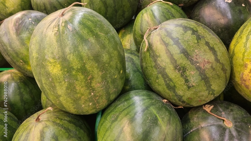 Pile of fresh watermelons (Citrullus lanatus) on the market. Watermelon is a sweet, commonly consumed fruit of summer. Watermelon juice can be blended with other fruit juices or made into wine. Pile of fresh watermelons (Citrullus lanatus) on the market. Watermelon is a sweet, commonly consumed fruit of summer. Watermelon juice can be blended with other fruit juices or made into wine.