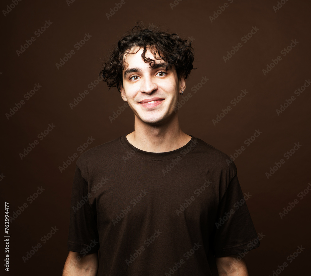 Obraz premium Handsome young smiling man wear brown t-shirt looking at camera on brown background