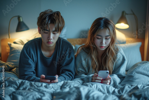 Asian young phone addict couple don't pay attention with each other. Family problem, New marriage man and woman partner lying down on bed, using smartphone, ignore husband and wife in bedroom at home. photo