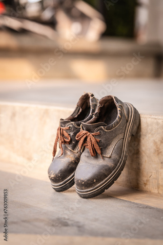 Men s brown leather shoes lying on the concrete floor. Shoes showing signs of use The leather is worn. Shoes were left on the floor.