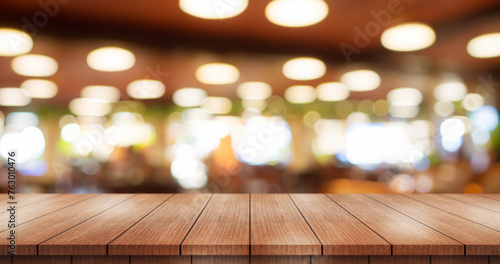 Empty wooden table top with lights bokeh on blur restaurant background.