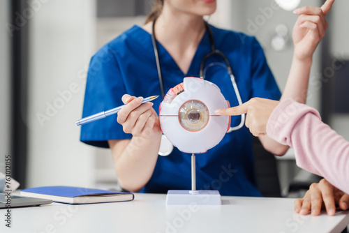 Female Caucasian ophthalmologist explains about eye diseases using the eye model with an Asian female patient At the table in the hospital examination room, Glaucoma, Cataract, Diabetic Retinopathy