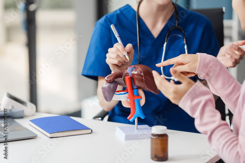 Caucasian liver professional female doctor explain to asian female patient using human liver model at desk in medical room, Liver cancer and Tumor, Jaundice, Viral Hepatitis A, B, C, D, E, cirrhosis