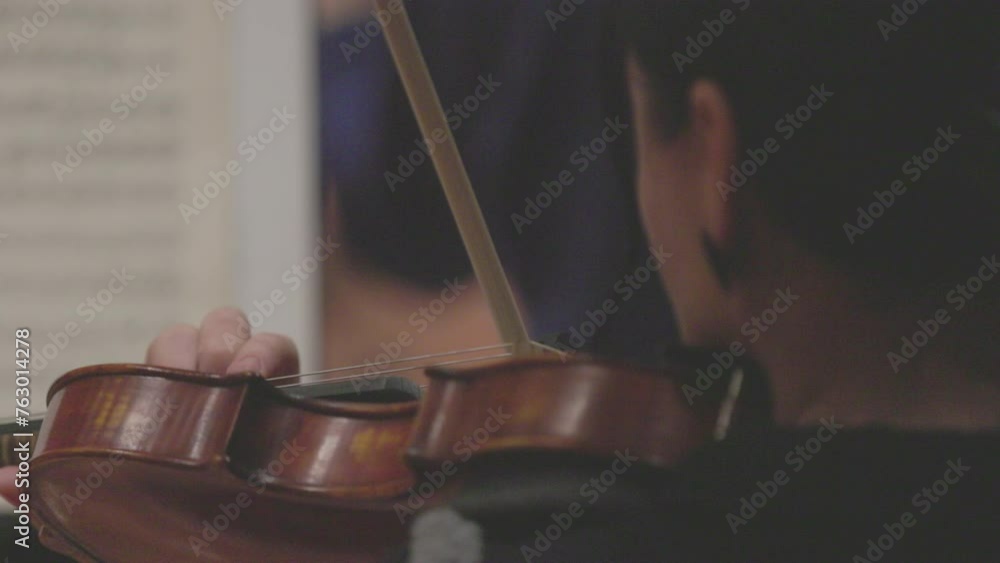 A slow motion video of a musician playing the violin or viola during a classical symphony orchestra rehearsal. Nr. 2