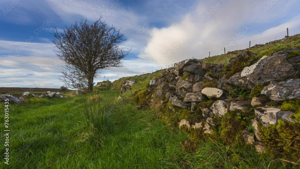 Timelapse of rural nature farmland with single tree in the foreground alongside a stonewall during sunny cloudy day viewed from Carrowkeel in county Sligo in Ireland. Timelapse of rural nature farmland with single tree in the foreground alongside a stonewall during sunny cloudy day viewed from Carrowkeel in county Sligo in Ireland.