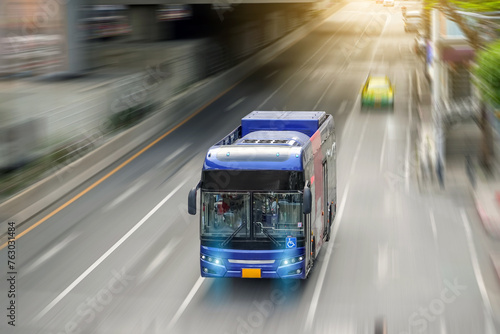 City bus rides along a metropolis street with its headlights on with motion rapid blur speed effect, aerial view