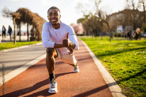 Young african-american man is exercising in the city. He is stretching his body.