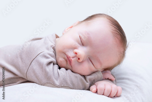 newborn sleeping baby on belly on light background, close-up, lifestyle, purity and innocence concept.