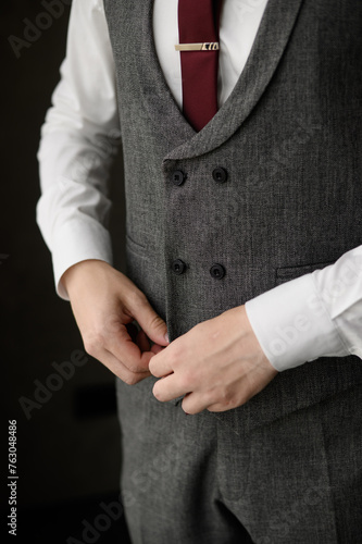 Fashionable business man wearing a tie fastening a button on a gray stylish jacket, close-up.Men fashion concept, wedding day, young modern businessman, men's stylish clothing