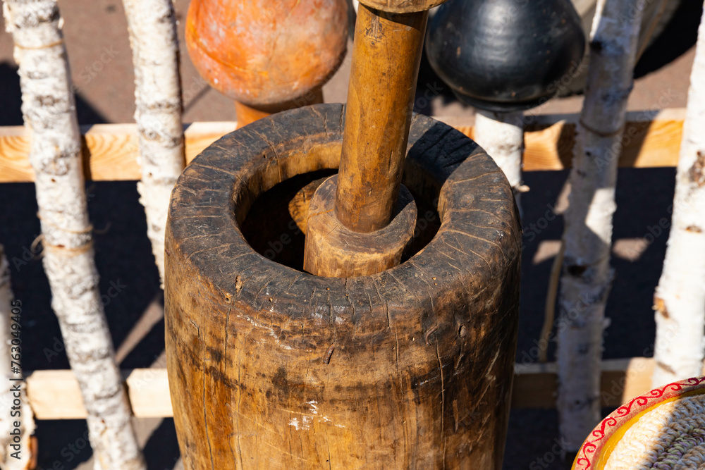 An old authentic wooden mortar with a wooden pestle in it, a mill. An old authentic wooden mortar with a wooden pestle in it, a mill.