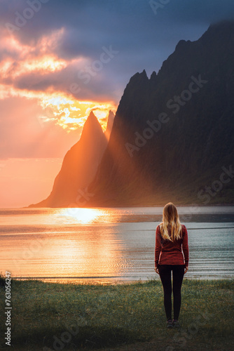 Woman walking on Ersfjord beach in Norway travel solo harmony with nature healthy lifestyle traveler exploring Senja island girl tourist enjoying sunset landscape sea and rocks summer vacation outdoor photo