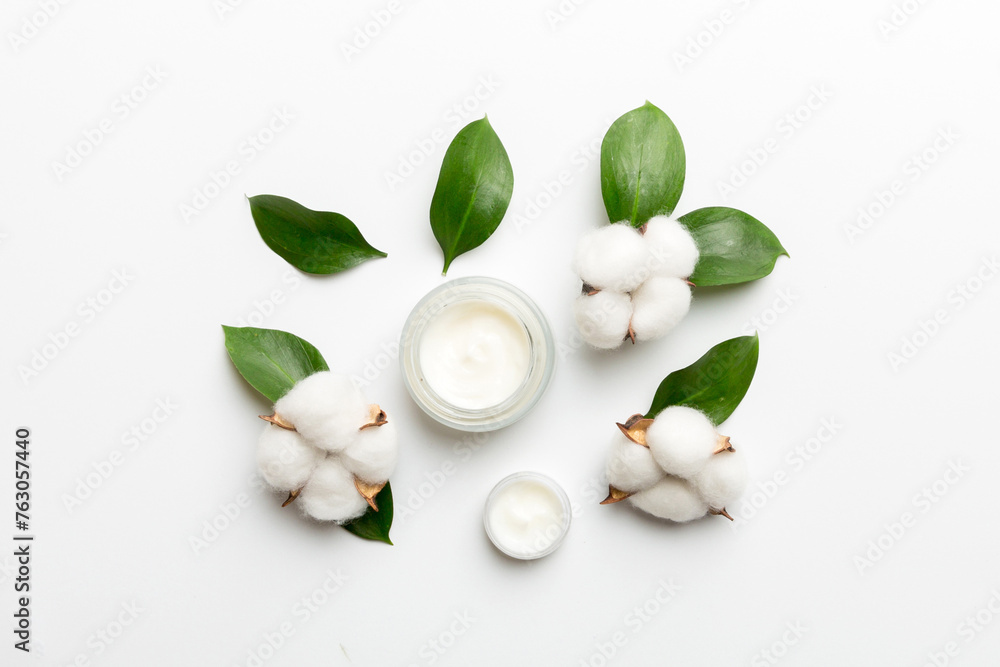 Organic cosmetic products with cotton flower and green leaves on white background. Flat lay