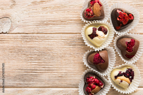 chocolate sweets in the form of a heart with fruits and nuts on a colored background. top view with space for text, holiday concept