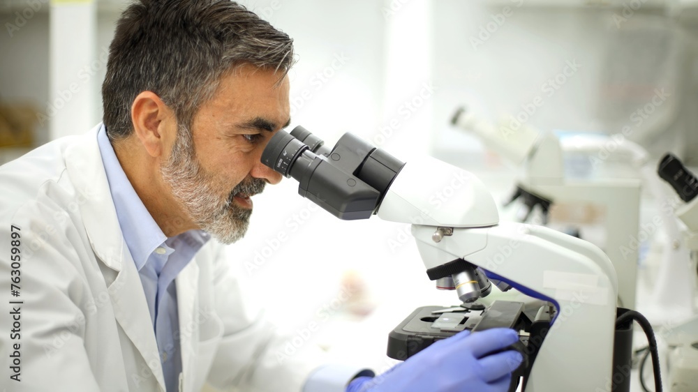 Focused scientist examining specimens with a microscope in a lab Focused scientist examining specimens with a microscope in a lab
