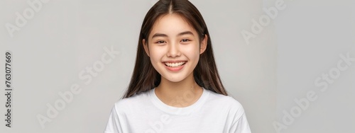 Beautiful korean girl smiling, white teeth, looking lovely at camera, standing in white tshirt over studio background photo