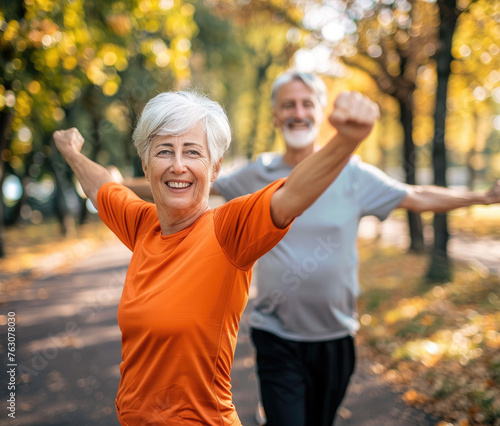 Happy senior woman stretching her arms while doing sport in the park with her husband, close up of arm and smiling face © Kien