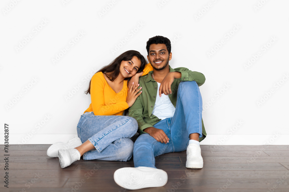 Affectionate hindu couple cuddling while seated on floor