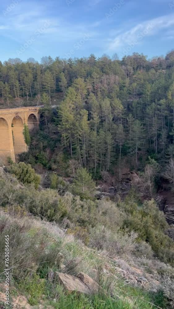 View of the canyon with a historical bridge and a mountain river below View of the canyon with a historical bridge and a mountain river below