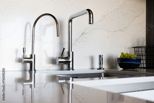 Kitchen brass utensils, chef accessories. Hanging modern kitchen with white marble wall and stone tabletop.