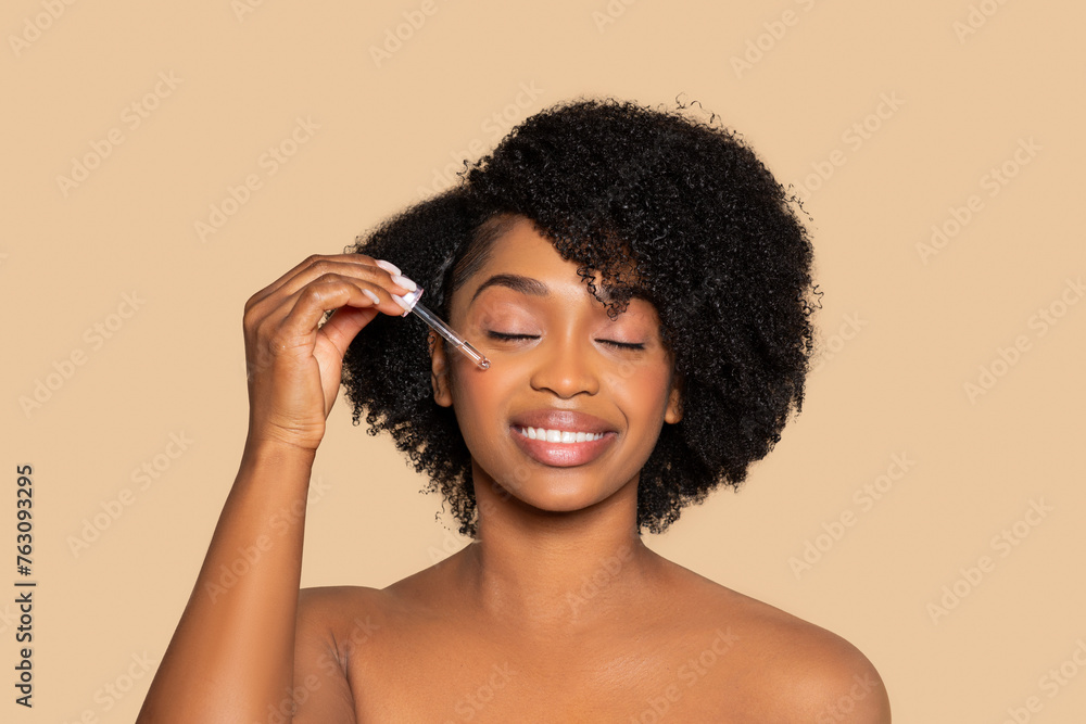 Content black woman applying serum, skincare ritual Content black woman applying serum, skincare ritual
