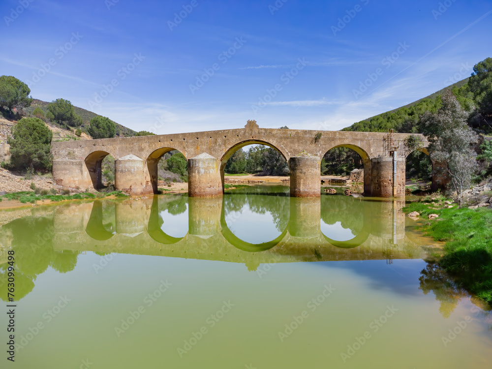 Aerial drone view of roman bridge in the hiking route of the water mills along the Odiel river from Sotiel Coronada, in Huelva province, Andalusia, Spain
