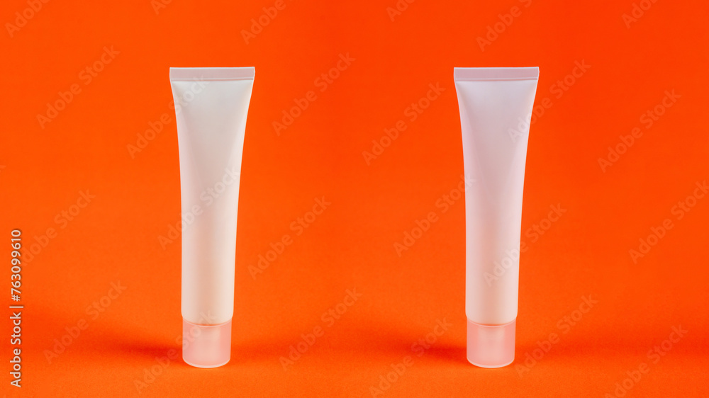 Plastic white tube for cream or lotion. Skin care or sunscreen cosmetic on orange background. Plastic white tube for cream or lotion. Skin care or sunscreen cosmetic on orange background.