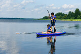 Children on SUP Paddle board playing with RC model boat