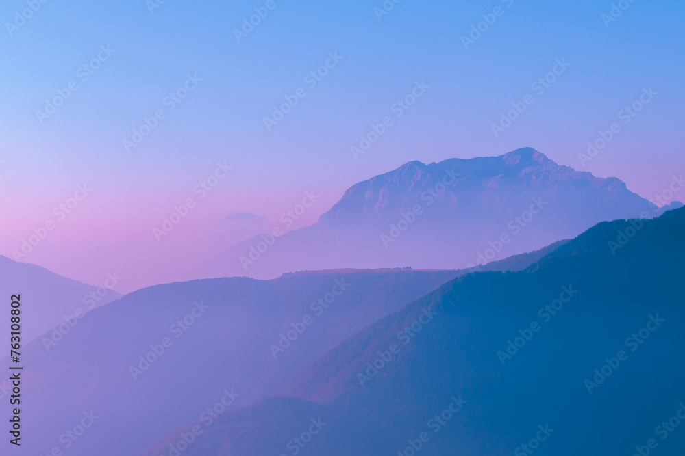 Spectacular mountain ranges silhouettes in shade of blue and pink.